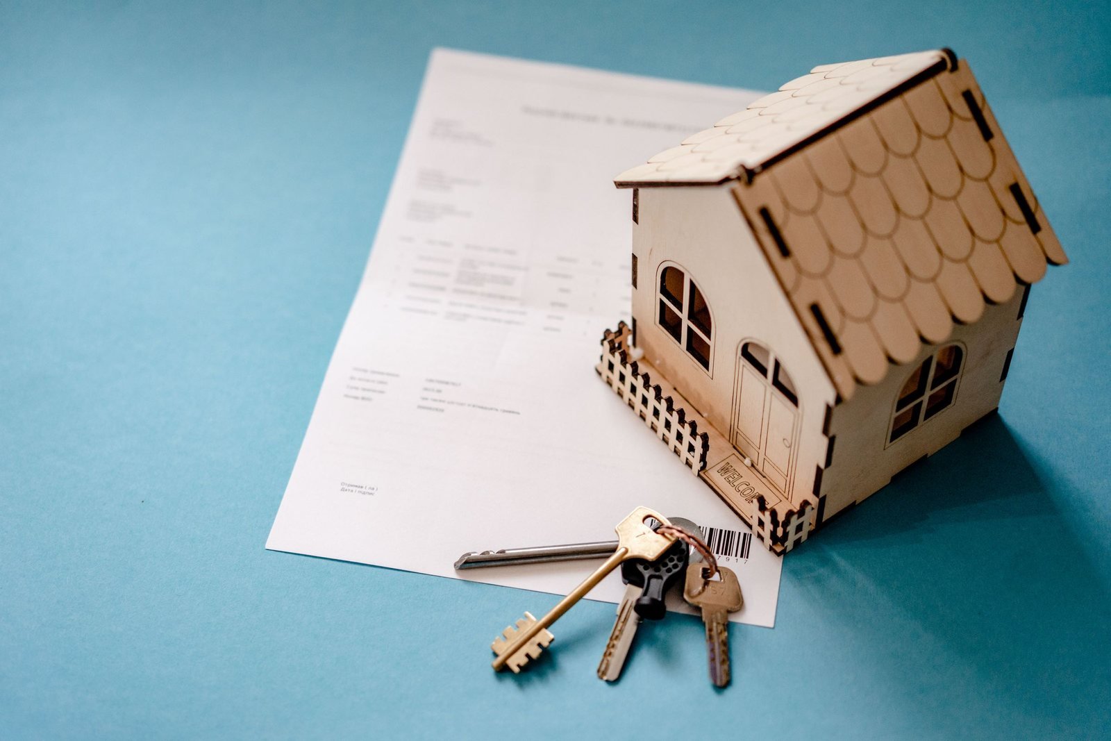 A model house with keys resting on a signed contract